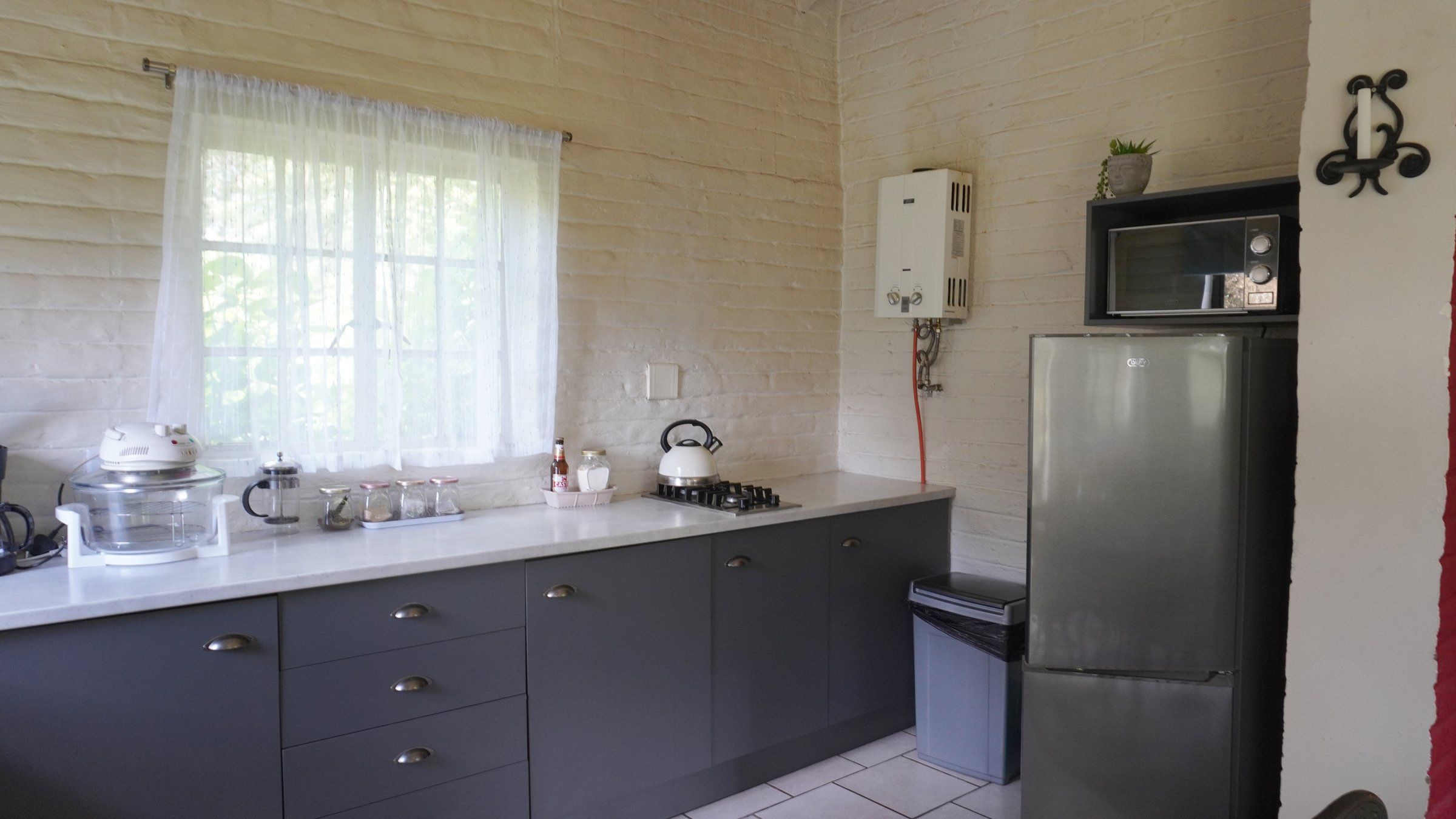 The Bird House kitchen, with a gas hob, fridge, microwave and a window onto the garden