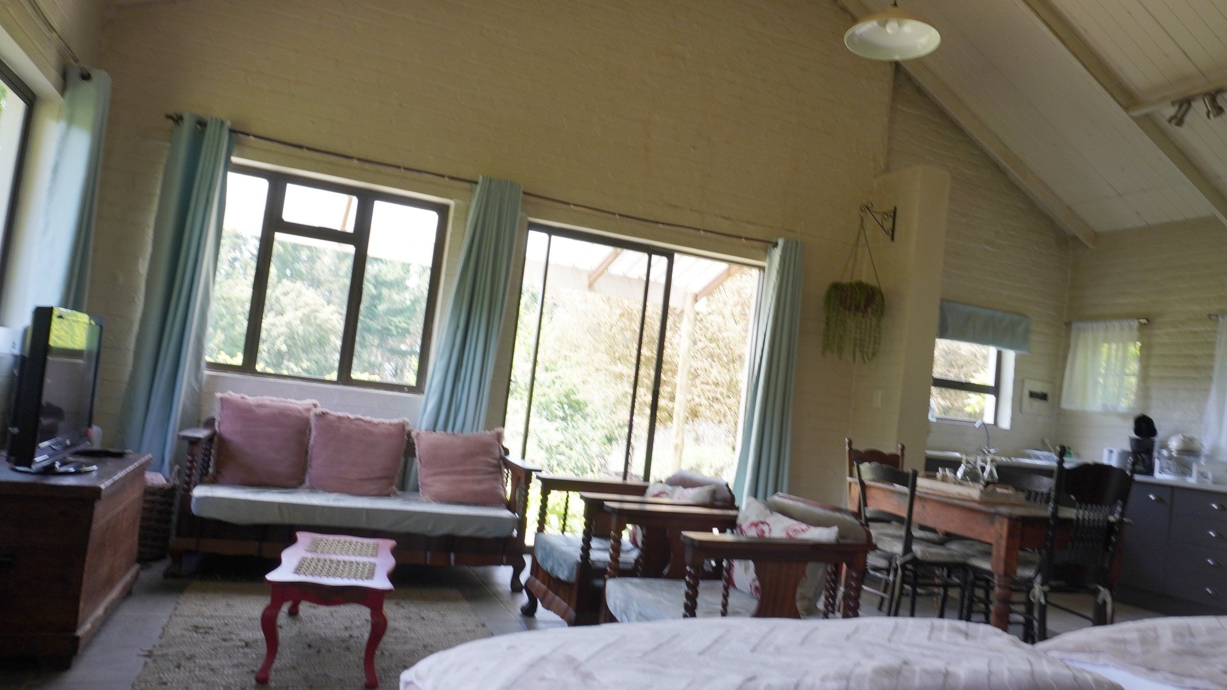 The sitting corner in The Bird House, with a sofa of pink cushions by the windows