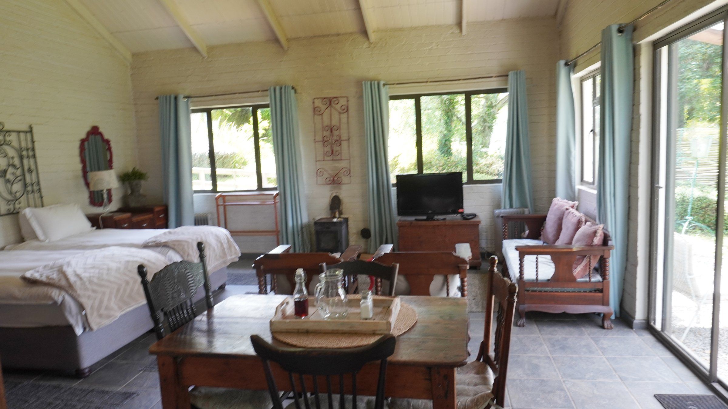 The Bird House's open-plan room: beds, dining table, sofa and sliding doors to the garden
