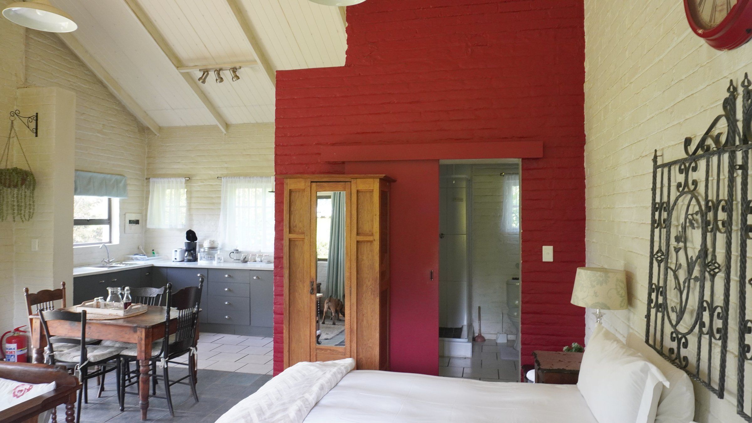 The Bird House from the bed: the red feature wall, the wardrobe, the bathroom door and the kitchen corner