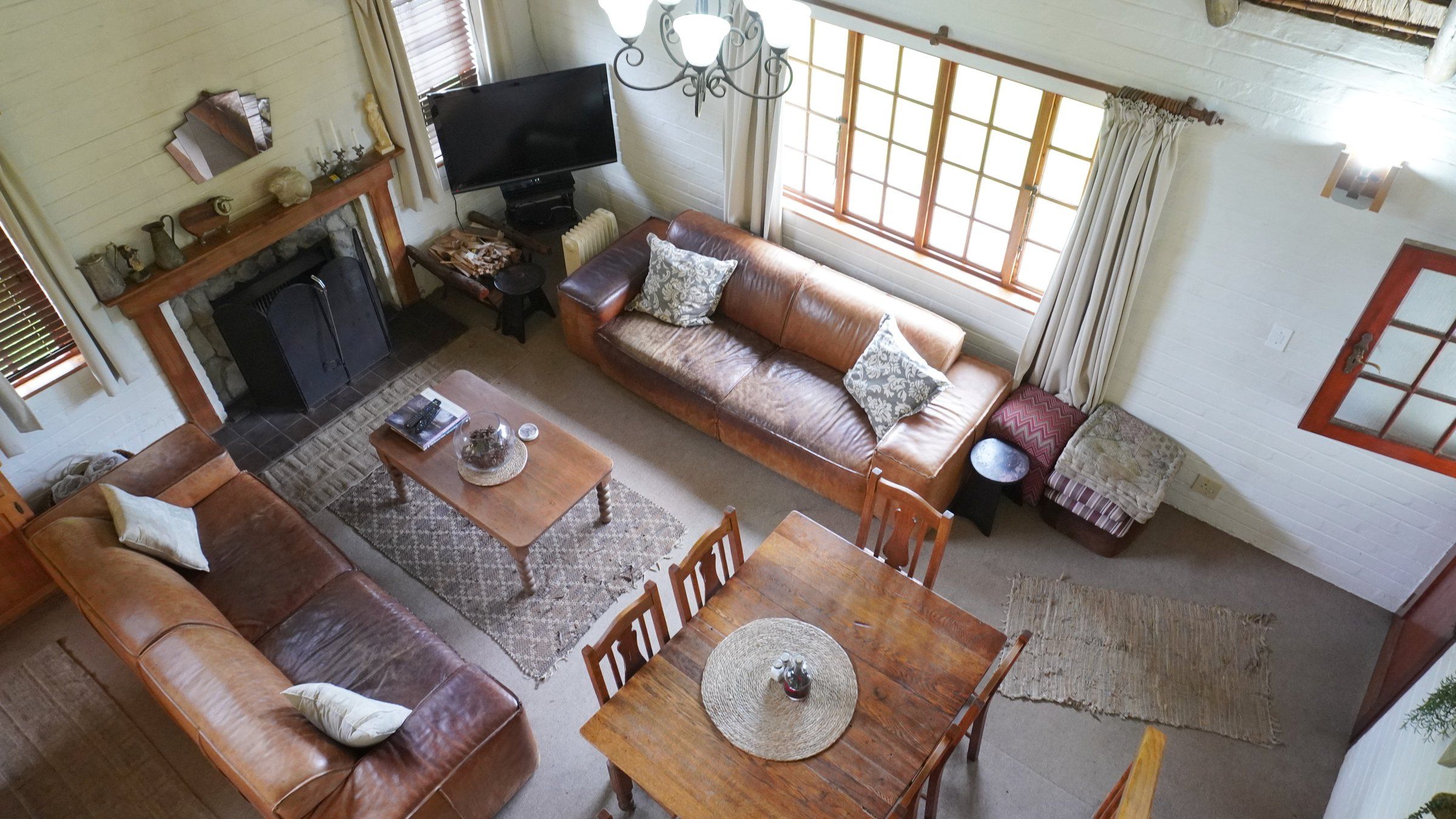 Looking down from the loft into De-vine View's lounge: leather sofas round a rug, the fireplace and the dining table