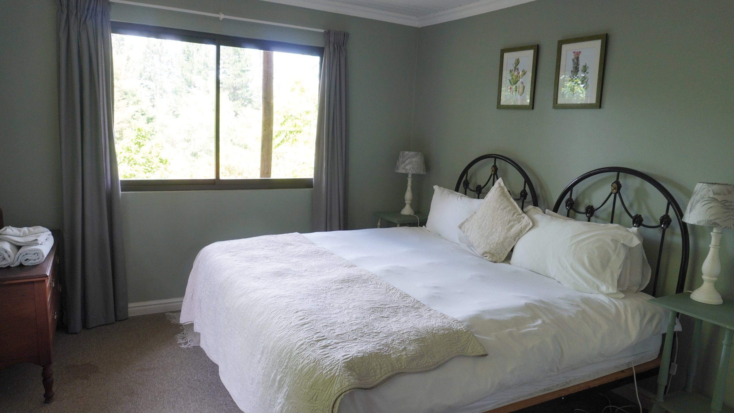 EverGreen Lodge bedroom two made up as a double, with iron bedheads and windows onto the trees